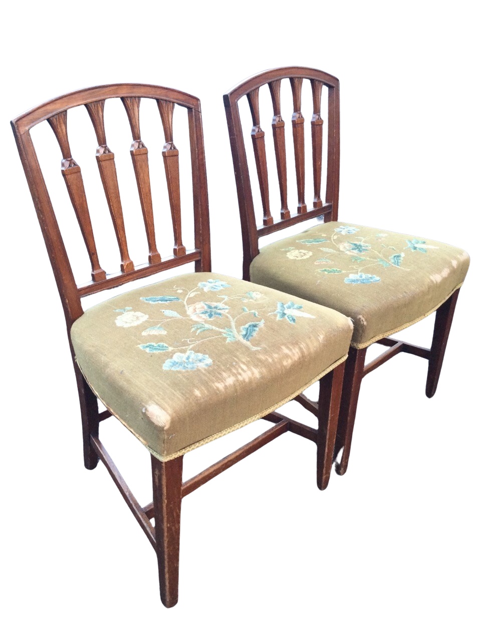 A pair of C19th mahogany Sheraton style chairs with arched backs framing leaf carved tapering