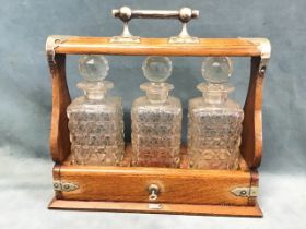 A late Victorian oak tantalus with silver plated mounts, the square cut glass decanters with ball