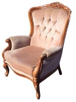 A Victorian style upholstered armchair with carved crestrail and buttoned back above a seat with