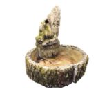 A composition stone garden water feature cast as faux logs beneath a channelled trunk with