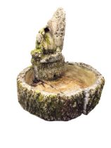 A composition stone garden water feature cast as faux logs beneath a channelled trunk with