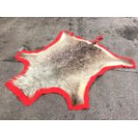 A shaggy animal skin rug on red baize ground. (68in x 86in)