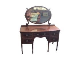 A bowfronted late Victorian mahogany dressing table with oval mirror on shaped supports above a