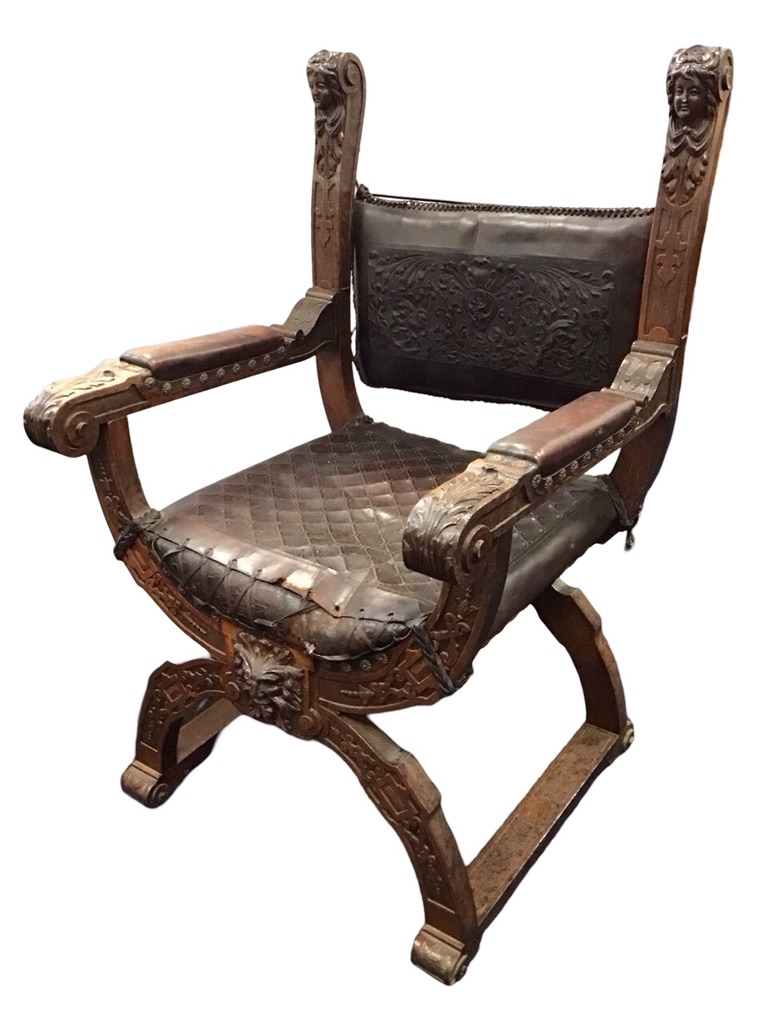 A C19th Renaissance style oak armchair with foliate stamped leather upholstered backrest on scrolled