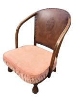 A 20s hardwood low armchair with studded embossed leather back and curved arms above a seat with