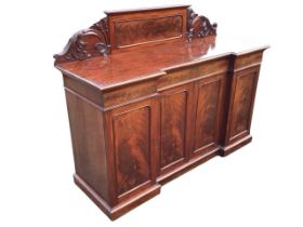 A Victorian mahogany inverted breakfront sideboard, the panelled back flanked by carved brackets,