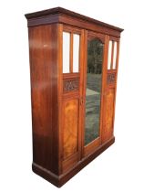 A Victorian mahogany wardrobe with moulded cornice above a central arched mirror door with foliate
