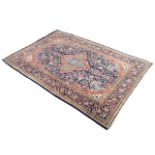 A Keshan wool rug with a quatrefoil floral medallion in a dense floral field on a blue ground,