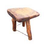 A naïve rustic stool with slab top on three branch legs united by wrought iron twisted
