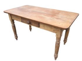 A Victorian pine table with rectangular rounded top above a frieze with knobbed drawer, raised on