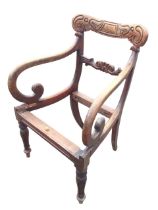 A William IV mahogany armchair with carved back and joining rail, having scrolled arms raised on