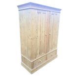 A Victorian style pine wardrobe with moulded cornice above a pair of panelled knobbed doors