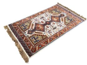 An Indian wool rug with a multitude lozenge motif amid stylised flowers & peacocks on a cream