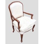 An upholstered armchair with rounded back in moulded frame above a seat with loose cushion, the arms