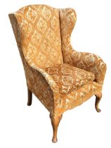 A Georgian style wing armchair with loose cushion and rounded arms above a sprung upholstered