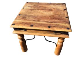A square hardwood coffee table with hammered wrought iron nailed decoration above a frieze with