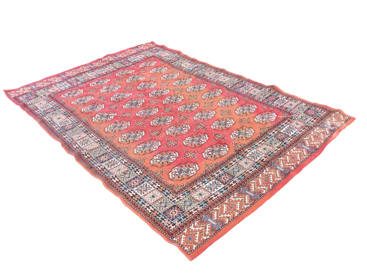 A Tekke style oriental rug woven with grid of oval floral medallions on red ground, framed by border