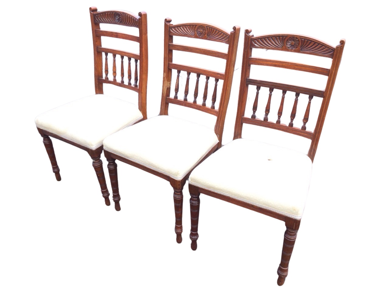 A set of three Edwardian mahogany chairs with arched gadrooned carved backs and central