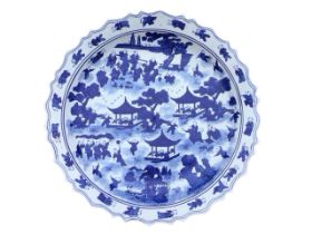 A large Chinese blue and white circular scalloped charger decorated with children in a garden amid