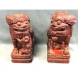 A pair of antique Chinese carved hardwood red lacquered dogs of fo candlestands with raised paw on