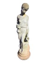 A composition stone garden statue cast as draped lady at the well holding a pitcher, raised on