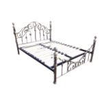 A Victorian style brushed brass double bed with arched scrolled headboard above spindles, the