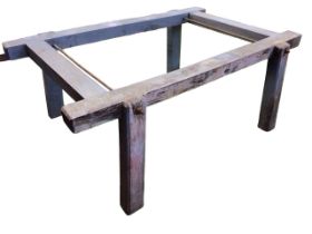 A chunky painted timber pig stand with rod bolts, the frame on rectangular chamfered angled legs. (