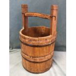An antique style coopered pine bucket with iron hoops to staves beneath wood bar yoke style