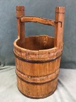 An antique style coopered pine bucket with iron hoops to staves beneath wood bar yoke style