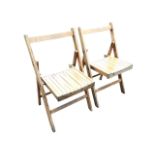 A pair of folding slatted beech chairs with dished batten seats and rounded backs to rectangular