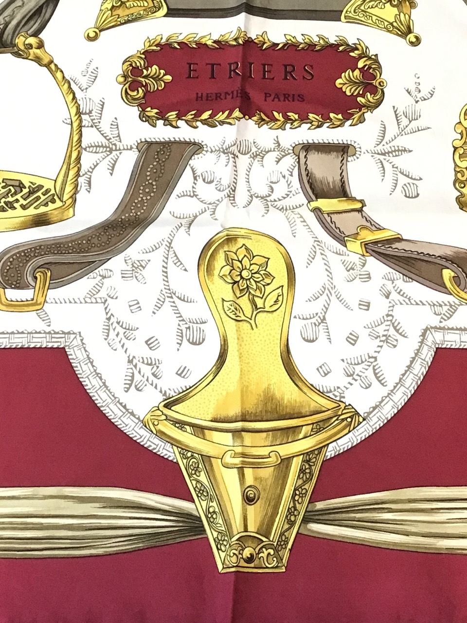 A silk Hermès scarf depicting a bell surrounded by various ornate stirrups, having deep red - Image 2 of 3