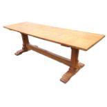 A pine refectory table with long rectangular top on shaped trestle type supports with sledge feet