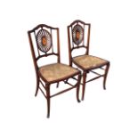 A pair of Edwardian mahogany chairs with shaped backs above pierced oval splats inlaid with fan