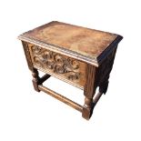 A rectangular oak box stool with moulded hinged lid above a scroll carved frieze framed by