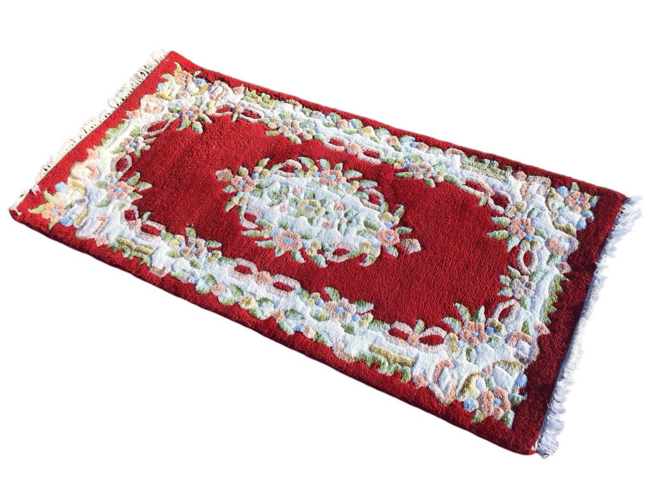 An Indian aubusson style rug with floral medallion on red ground within conforming floral