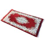 An Indian aubusson style rug with floral medallion on red ground within conforming floral
