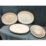 A set of three oval Adams ironstone graduated meat dishes with floral swag borders; a Booths ashet