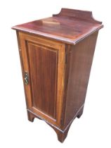 An Edwardian mahogany pot cupboard with moulded top above a chevron banded panelled door, having