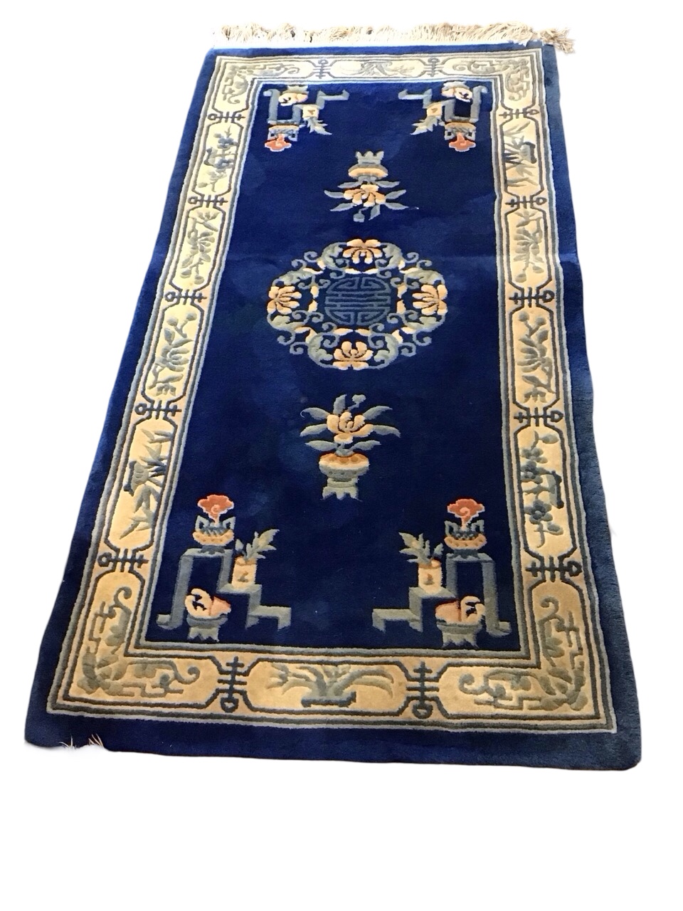 A Chinese wool carpet with central floral Shou medallion on a blue field with plantpots, braziers