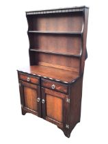 A stained oak dresser, the notched cornice and dentil apron above shelves flanked by shaped sides