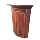 A C19th mahogany bowfronted hanging corner cabinet, the deep cornice and frieze above a pair of