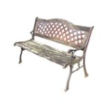 A garden bench with arched latticework panel to back above a wood slatted seat, raised on sabre legs