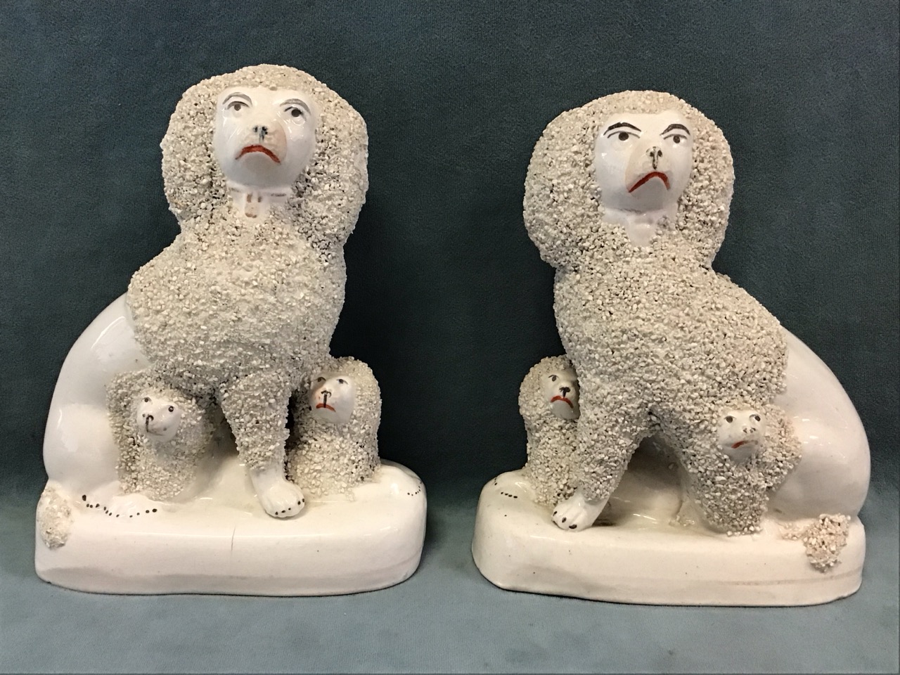 A pair of Victorian Staffordshire flatback ceramic seated poodles, each with two puppies. (6.