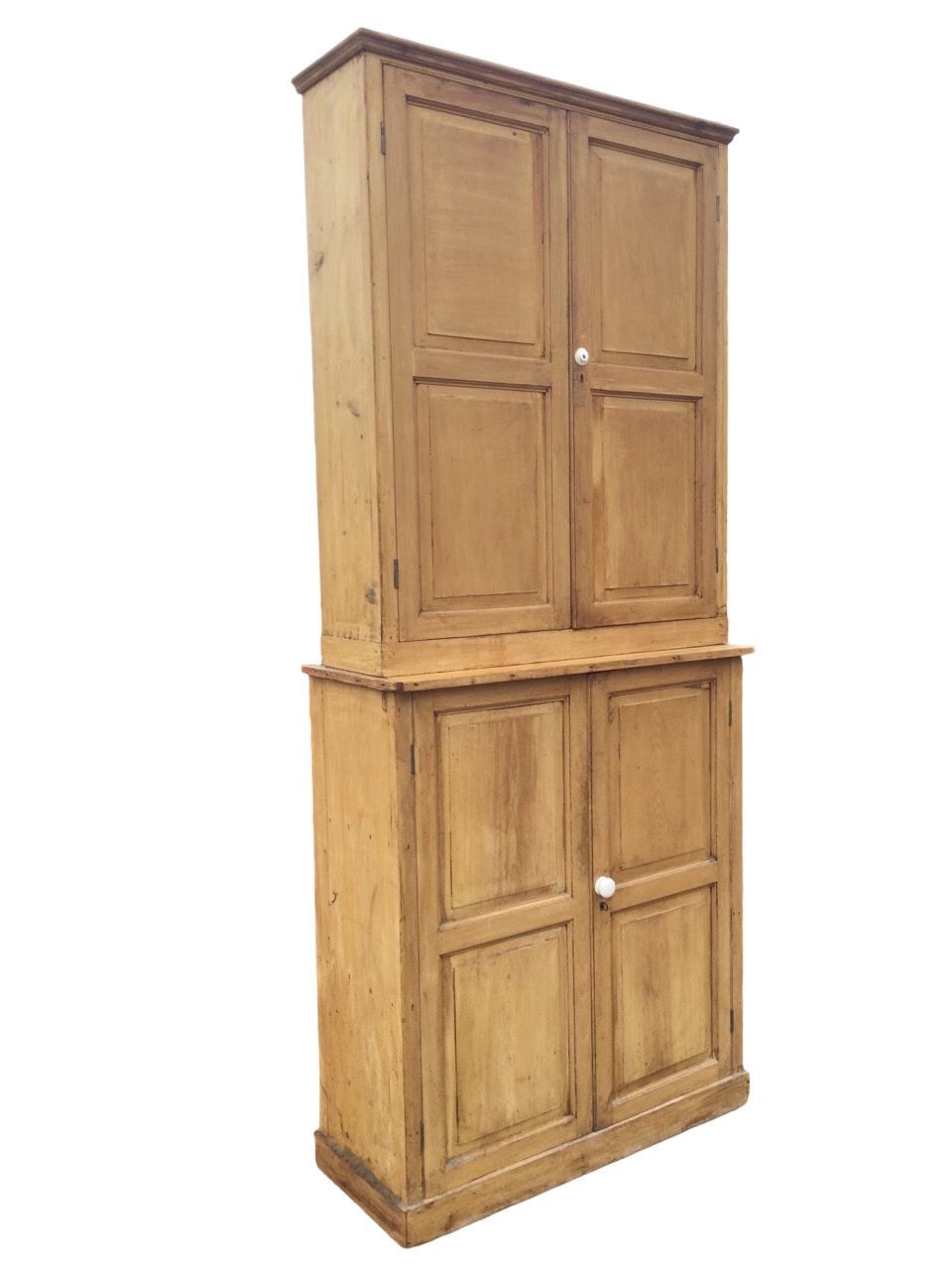 Two Victorian pine cupboards married to make a tall cabinet, each piece with four fielded panelled