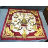 A silk Hermès scarf depicting a bell surrounded by various ornate stirrups, having deep red