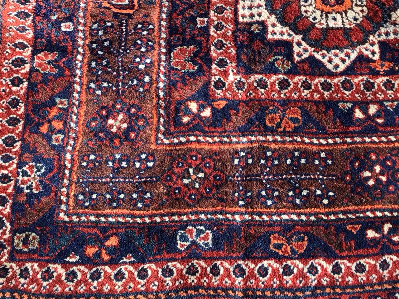 A Shiraz wool carpet with flowerhead lozenge medallion amid profuse flowers on a red field with - Image 2 of 3