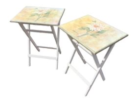 A pair of painted folding occasional tables, the rectangular tops decorated with floral prints,