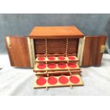 A mahogany coin cabinet with rectangular top above a pair of doors enclosing fourteen brass