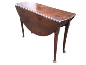 A Georgian mahogany drop-leaf dining table, the circular top with two leaves supported on swing