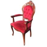 A mahogany armchair with button upholstered back with carved crest above a flared serpentine